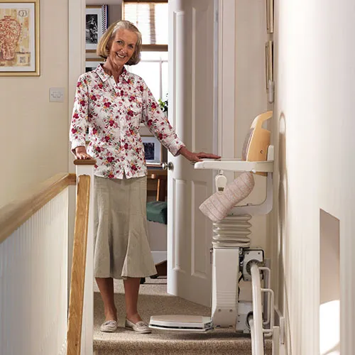 Woman at the top of her stairs with a percher stairlift in Greenock